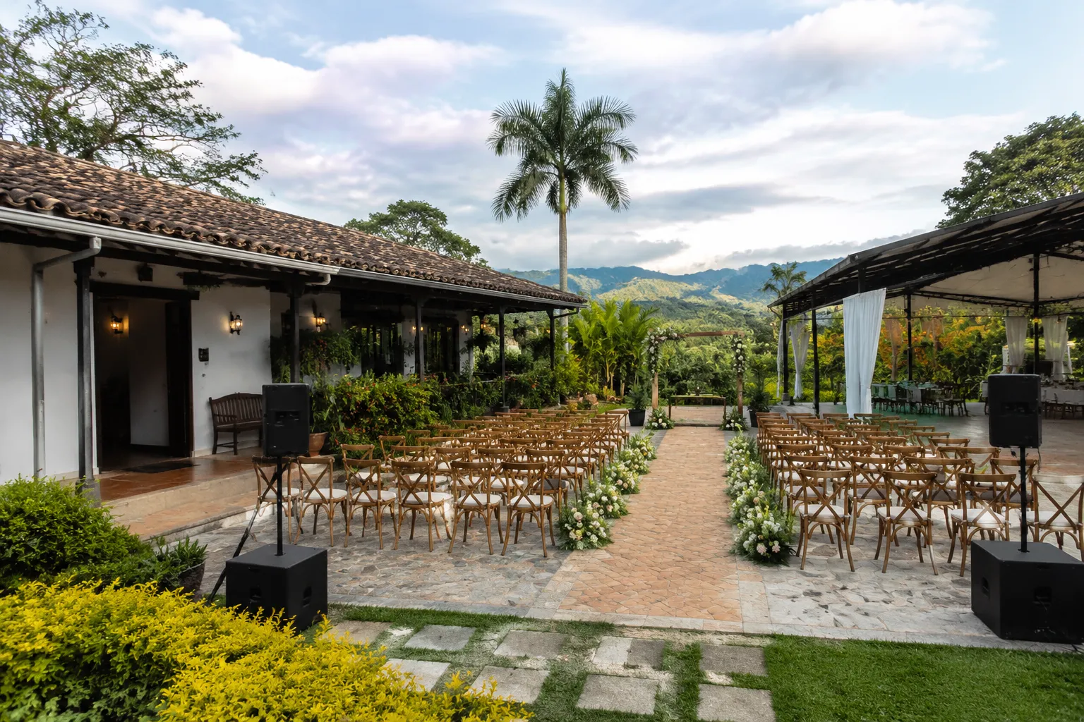 Outdoor Colombian wedding venue showing ceremony seating, access paths, and a sheltered backup area